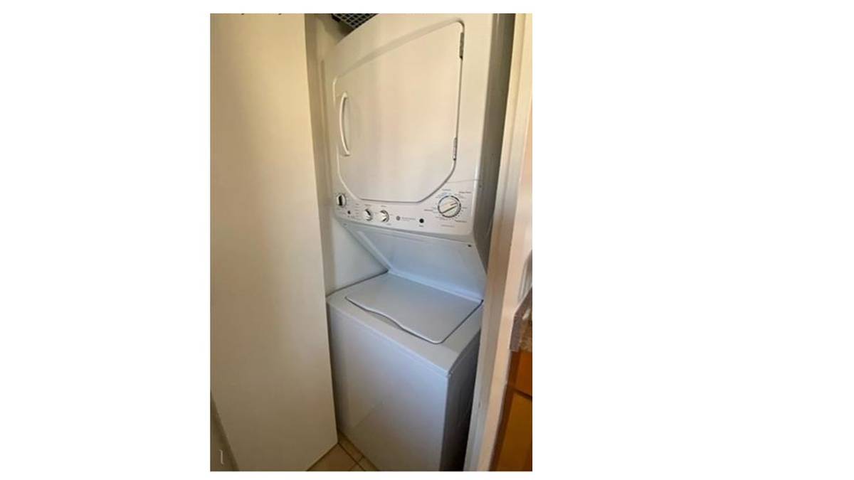 A white washing machine is placed in a narrow space.
